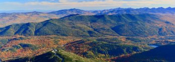 Fall scene of forest-clad Adirondack mountains upon mountains fading into distance.